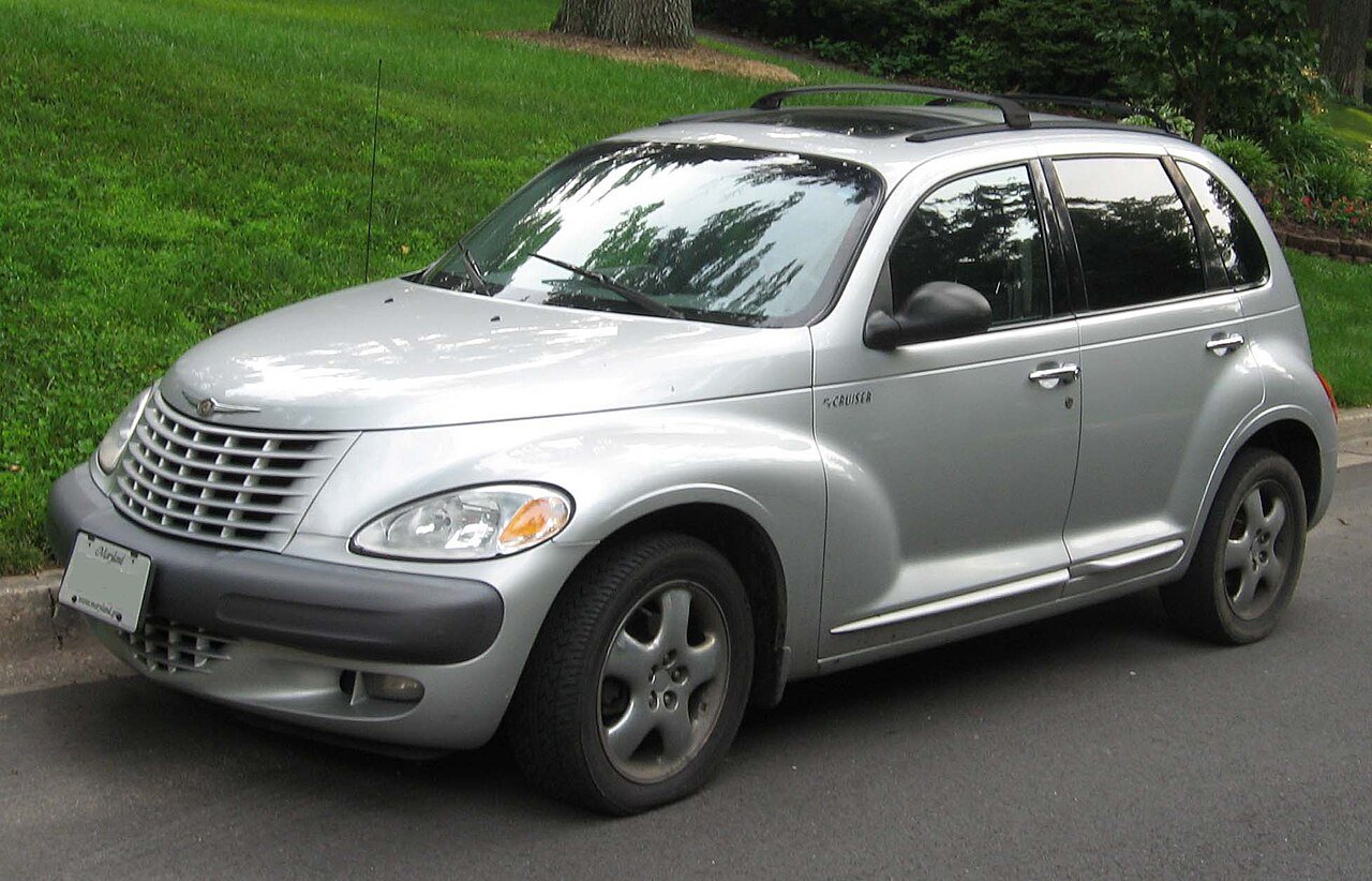 Ασημί Chrysler PT Cruiser σταθμευμένο σε δρόμο με γρασίδι στο παρασκήνιο.