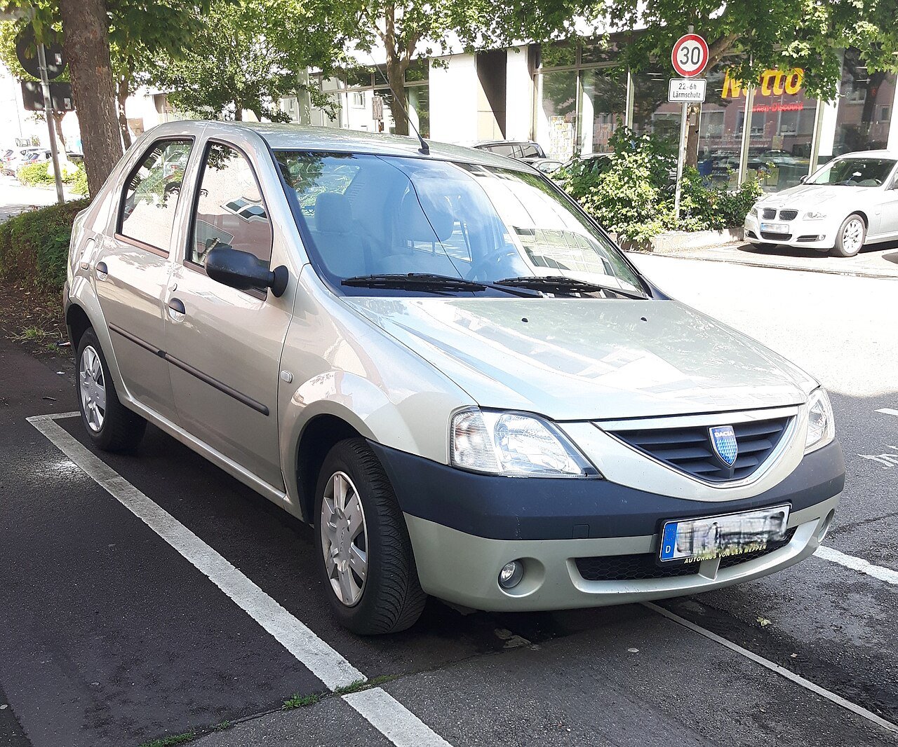 Ασημί Dacia Logan σταθμευμένο σε αστικό περιβάλλον.
