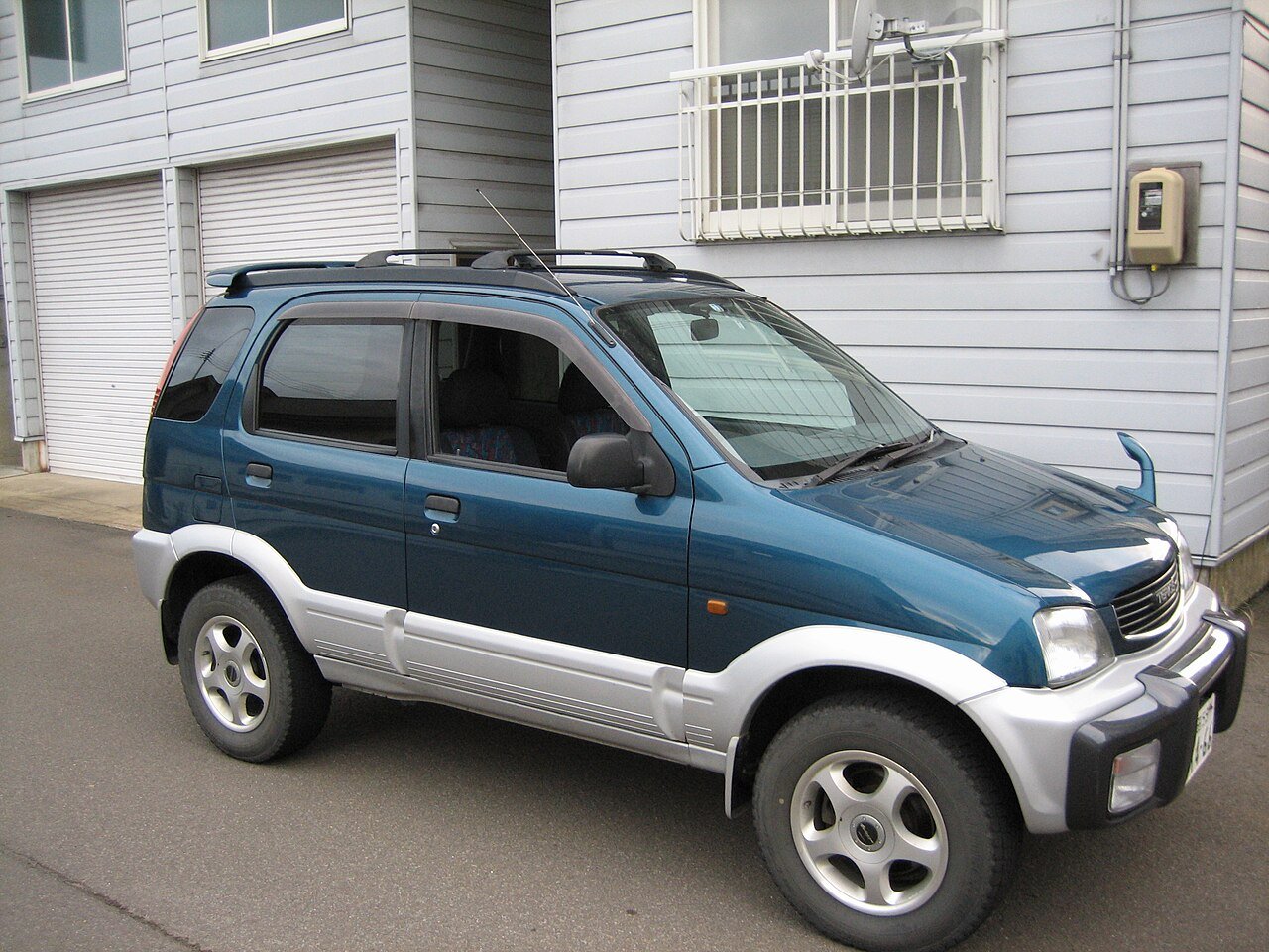 Ένα μπλε Daihatsu Terios σταθμευμένο μπροστά σε ένα κτίριο.