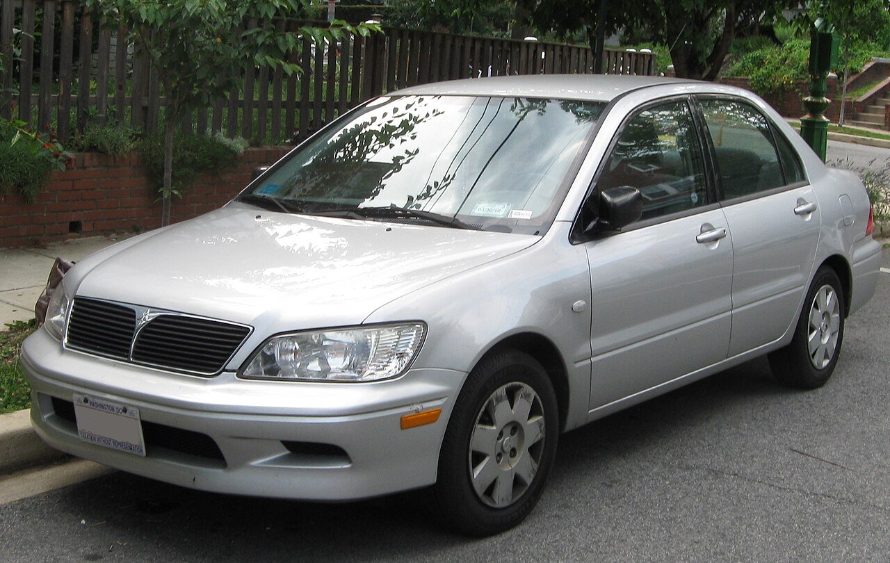 Ασημί Mitsubishi Lancer σταθμευμένο στο δρόμο, μπροστινή όψη.