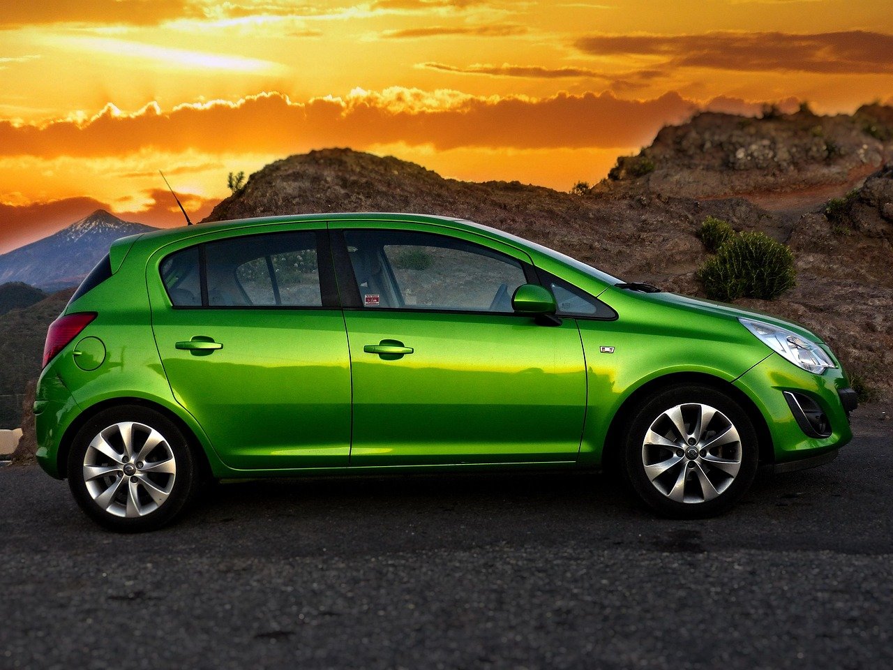 Πράσινο Opel Corsa παρκαρισμένο σε ορεινό δρόμο με ηλιοβασίλεμα.
