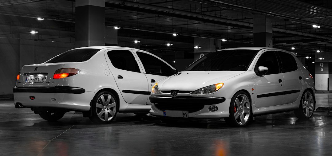 Δύο λευκά Peugeot 206 παρκαρισμένα σε υπόγειο γκαράζ.