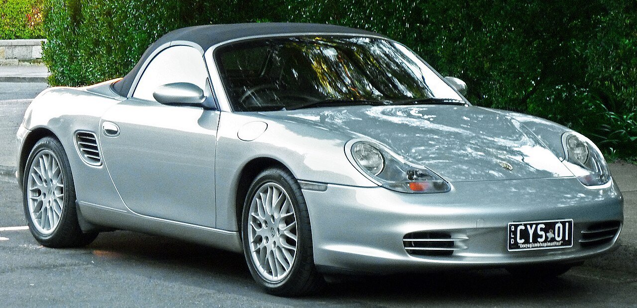 Ασημί Porsche Boxster με μαύρη οροφή παρκαρισμένη σε δρόμο.