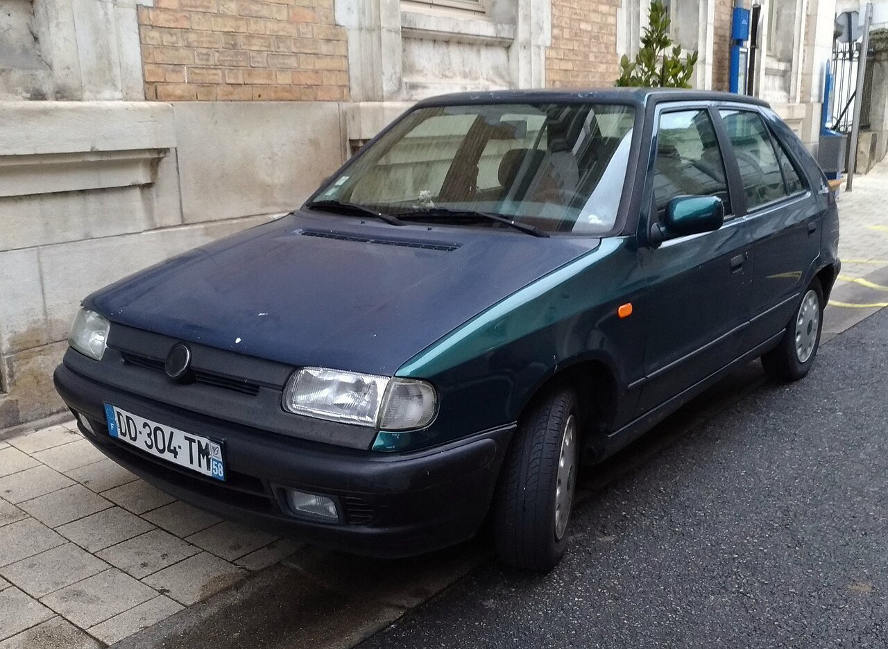 Σκούρο μπλε Skoda Felicia παρκαρισμένο σε πεζοδρόμιο, με φθαρμένο χρώμα.