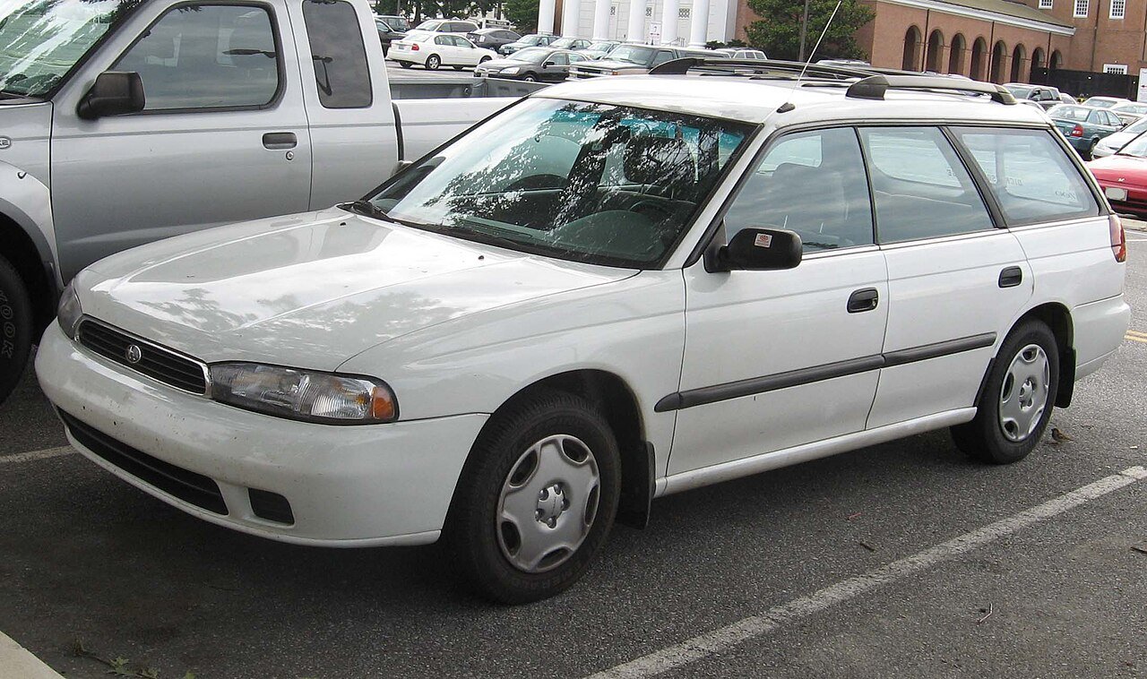 Λευκό Subaru Legacy station wagon σταθμευμένο σε εξωτερικό χώρο.