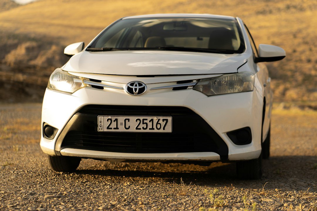 Λευκό Toyota Yaris παρκαρισμένο σε χωματόδρομο με ξηρό τοπίο.