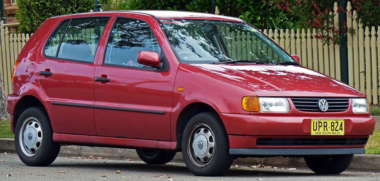 Κόκκινο Volkswagen Polo, παλαιότερης γενιάς, παρκαρισμένο σε δρόμο.
