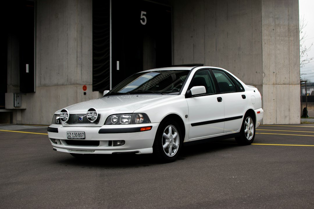 Λευκό Volvo S40 παρκαρισμένο μπροστά σε ένα γκρίζο κτίριο.